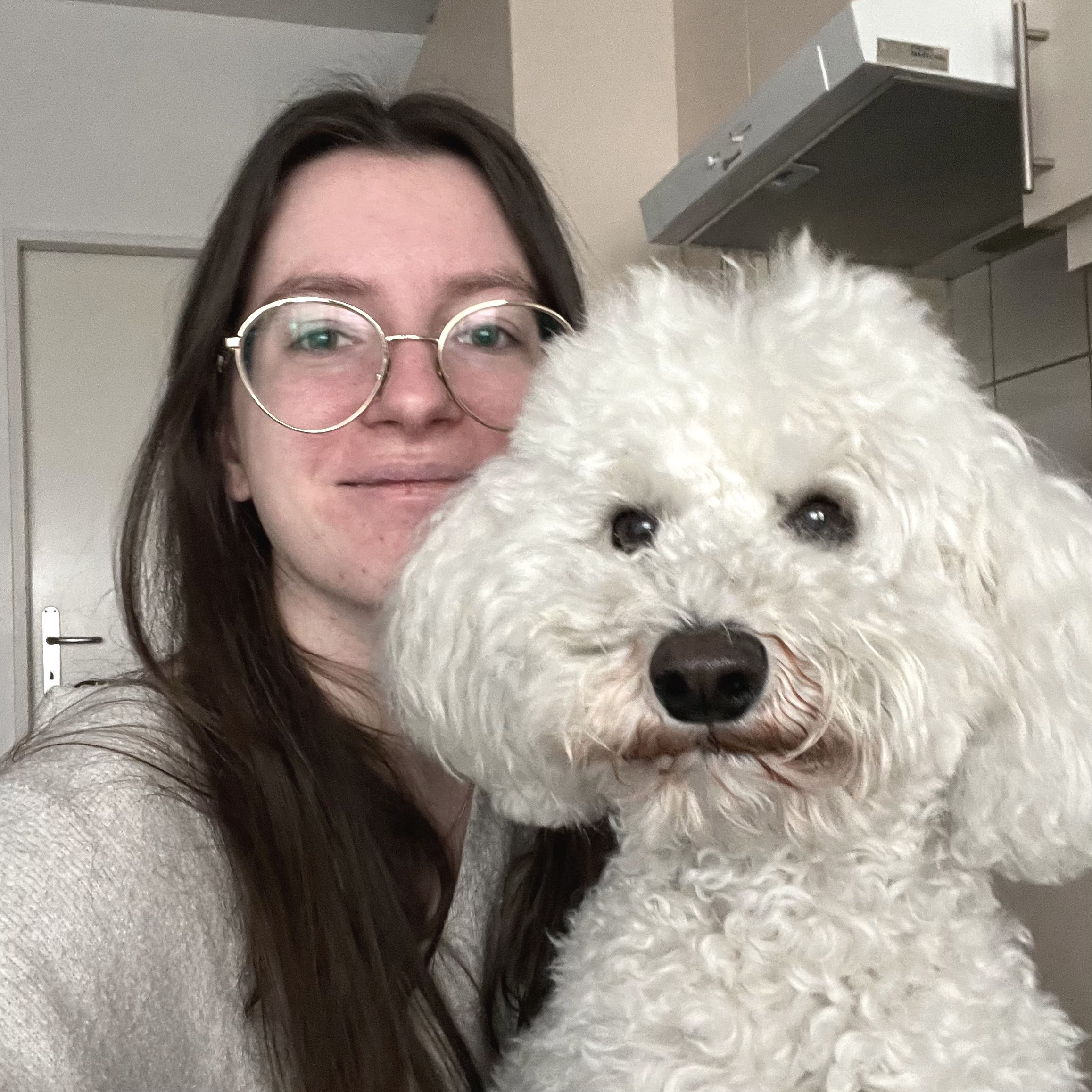 Femme brune blanche souriante et moyen chien caniche doodle blanc de face
